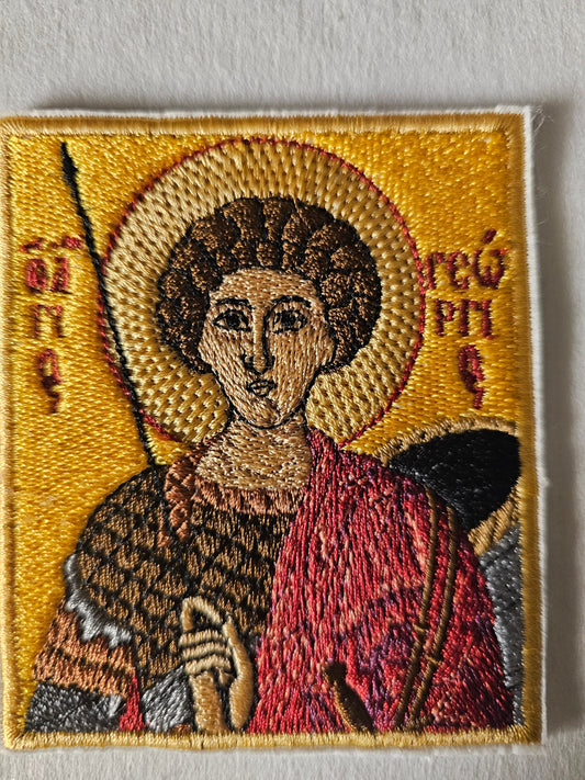 Embroidered religious icon with yellow background, figure in red and brown robes