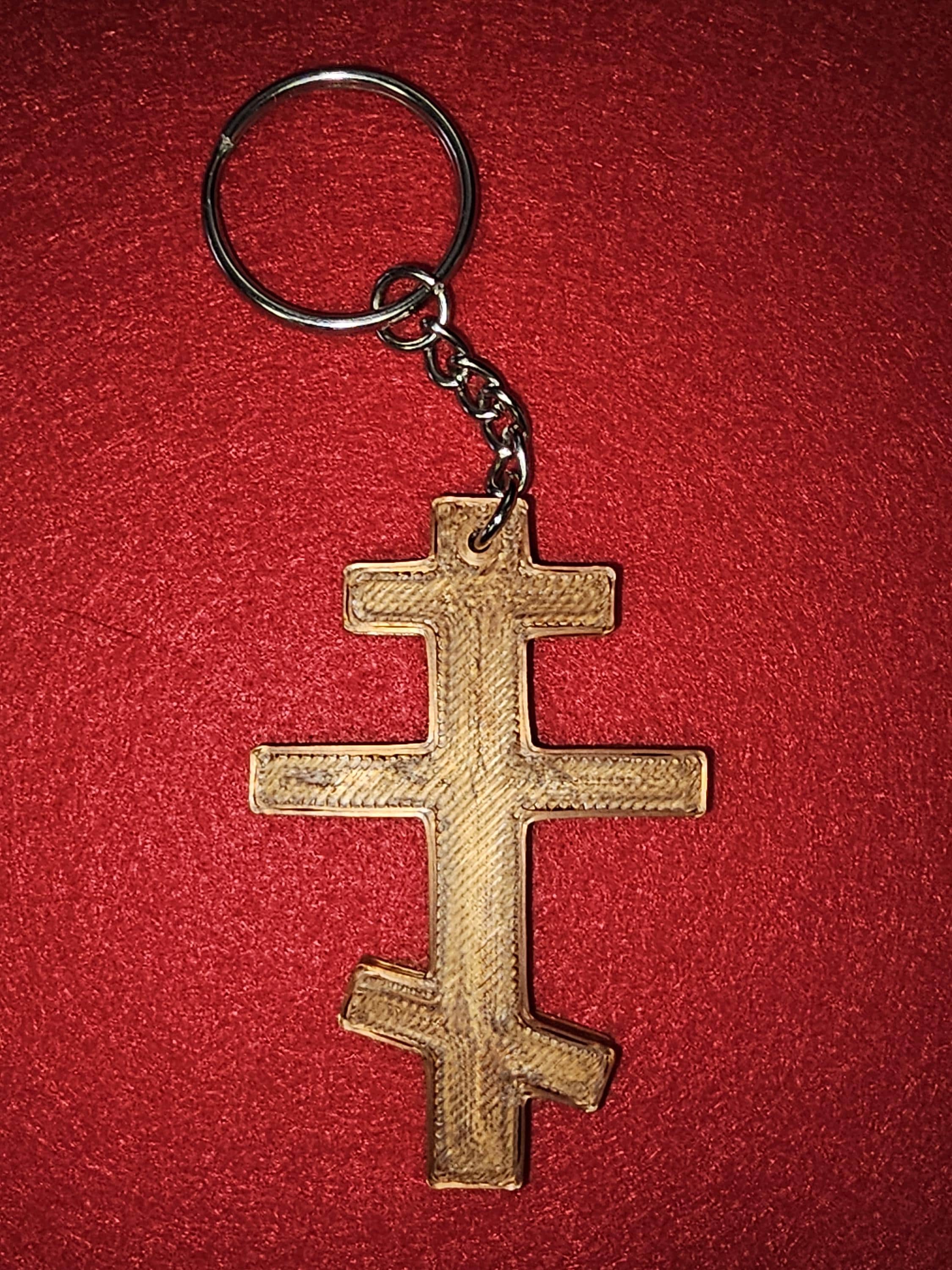 Wooden Orthodox cross keychain on red textured fabric background